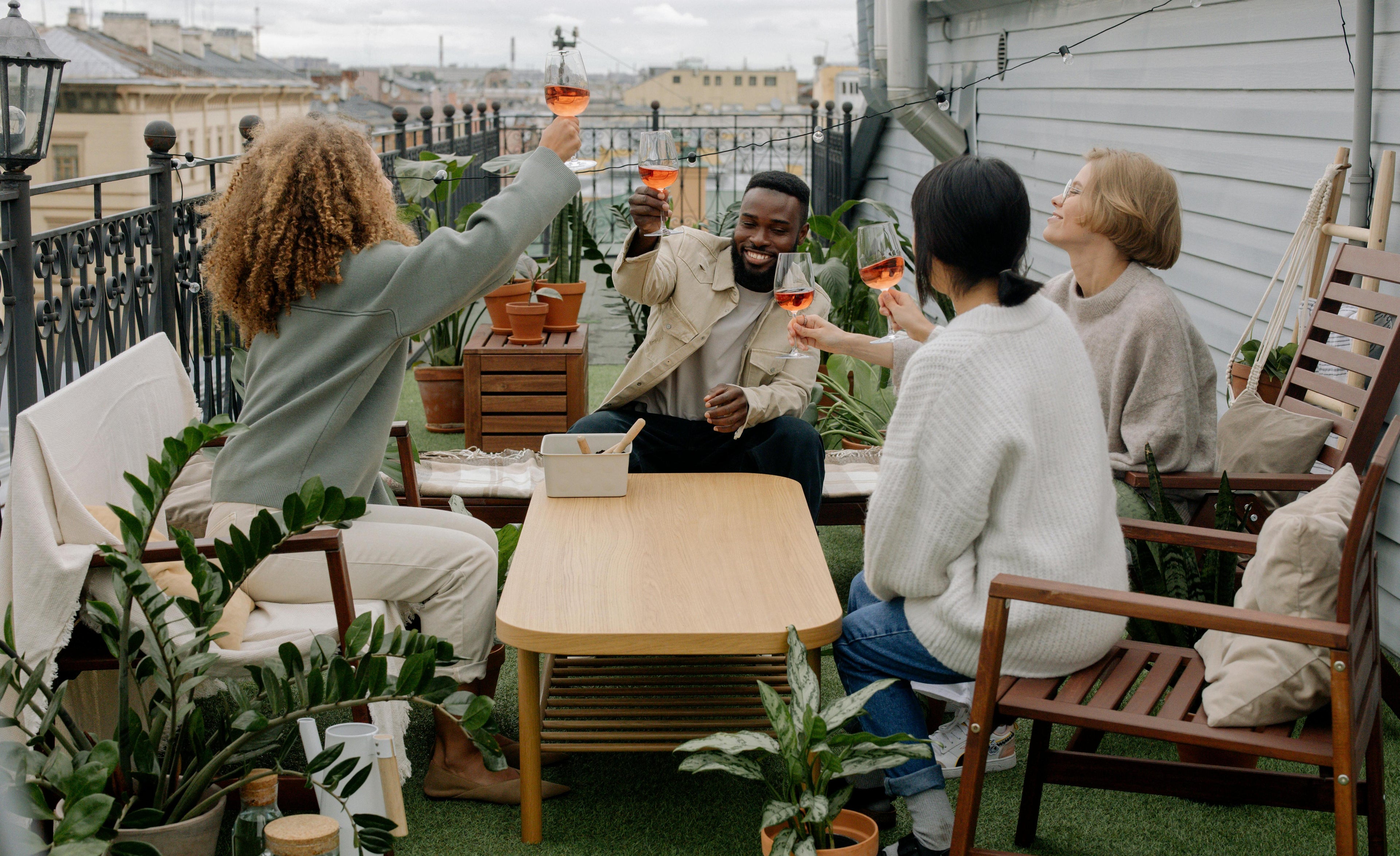 Groupe d'amis sur terrasse maison qui porte un toast avec vin rosé fait maison