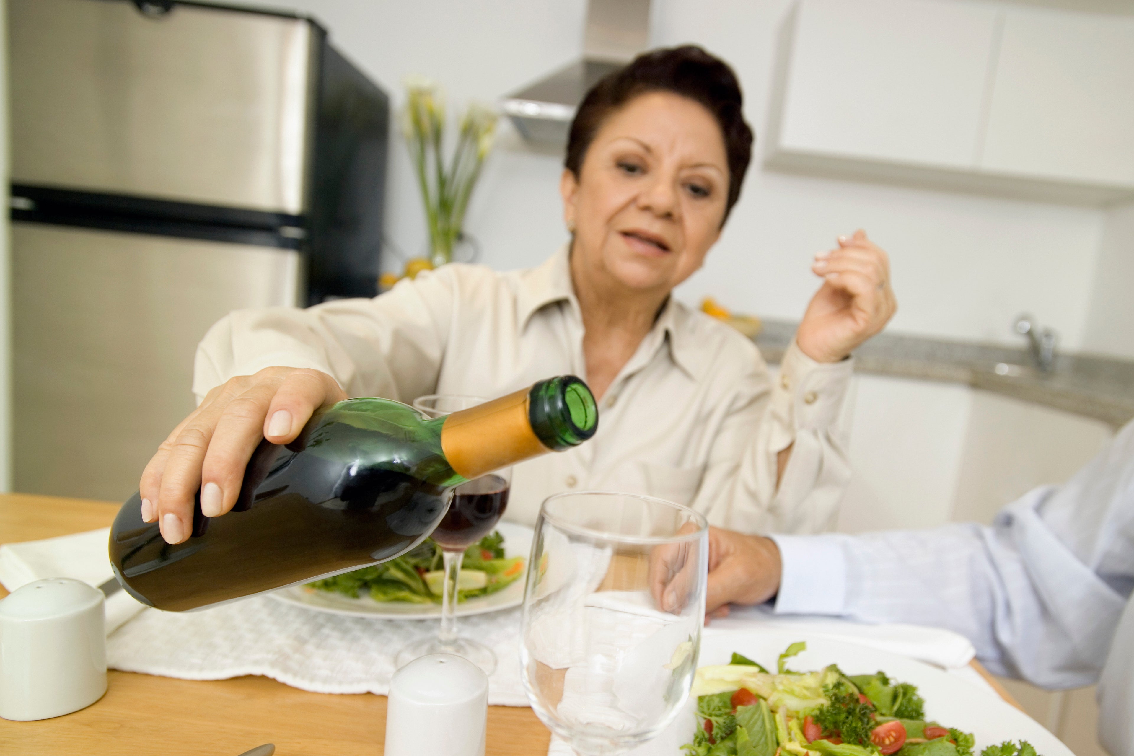 Une femme qui sert du vin rouge fait maison lors d'un souper